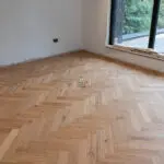 Elegant natural oak herringbone engineered wood flooring, featuring precise V-shaped patterns, rich wood textures, and a durable multi-layered construction