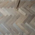 Trade 12mm Smoked Washed Grey Oak Herringbone Engineered Wood Flooring with soft grey tones and a classic herringbone pattern
