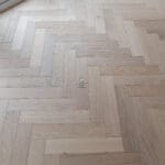 Invisible Light Oak Herringbone Engineered Wood Flooring with a subtle matte finish, showcasing light oak tones and a precisely arranged herringbone pattern