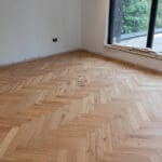 Elegant natural oak herringbone engineered wood flooring, featuring precise V-shaped patterns, rich wood textures, and a durable multi-layered construction