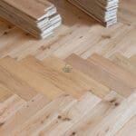 Elegant natural oak herringbone engineered wood flooring, featuring precise V-shaped patterns, rich wood textures, and a durable multi-layered construction