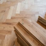 Elegant natural oak herringbone engineered wood flooring, featuring precise V-shaped patterns, rich wood textures, and a durable multi-layered construction