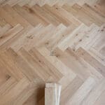 Elegant natural oak herringbone engineered wood flooring, featuring precise V-shaped patterns, rich wood textures, and a durable multi-layered construction