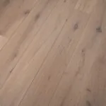 Close-up view of Nevada 14/3 x 190mm classic white oiled oak engineered wood flooring, featuring wide planks, natural knots, soft light tones, and textured wood grain pattern
